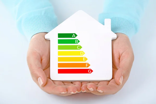 Female hands holding house with energy efficiency scale image