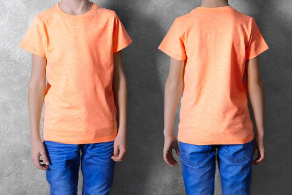 Reklam giysileri. Şeftali T-shirt ve jeans gri duvar arka plan üzerinde çocuk — Stok fotoğraf