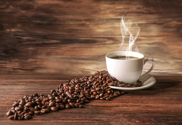 Kopp kaffe med korn på trä bakgrund — Stockfoto