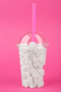 Plastik yüzlü fincan Lump & şeker ve pembe bir arka plan üzerinde kokteyl tüp ile