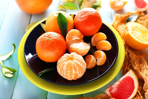 Fresh citrus fruits with green leaves on wooden table closeup — Stock Photo, Image