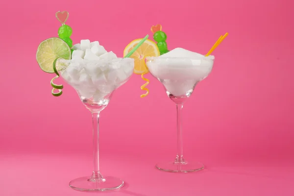 Margarita-Gläser mit Klumpen, Kristallzucker, Cocktailhalmen und Zitrusscheiben auf rosa Hintergrund — Stockfoto