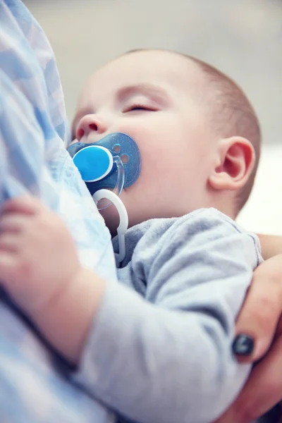 Baby with dummy sleeping in mother's hands — Stock Photo, Image