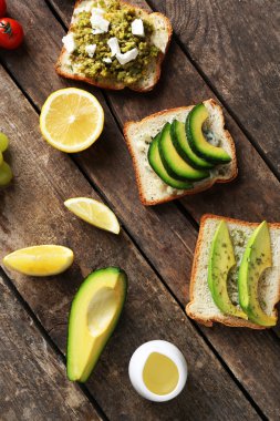 Koyu ahşap zemin üzerine sebzeli avokado sandviç