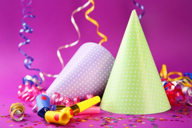 İki doğum günü şapka ile serpantin flama ve mor arka plan gürültü makineleri