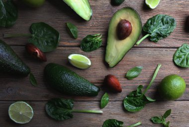 Ahşap arka plan üzerinde avokado taze ıspanak, fesleğen ve kireç ile dilimlenmiş