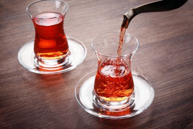 Ahşap masa üzerinde cam bardak içine dökme siyah çay