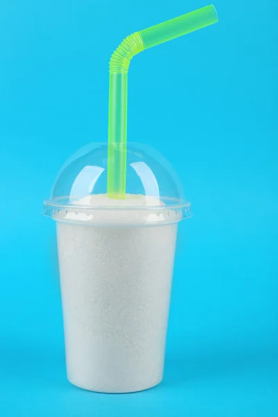 Пластиковая чашка смузи с гранулированным сахаром и коктейльной трубкой на синем фоне — стоковое фото