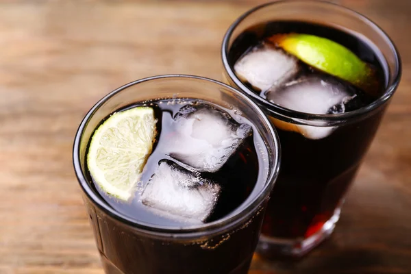 Cocktails met kalk plakjes en ijsblokken op houten tafel, close-up — Stockfoto