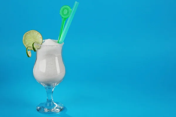 Hurricane glass with granulated sugar, cocktail tube and lime slice on blue background — Stock Photo, Image