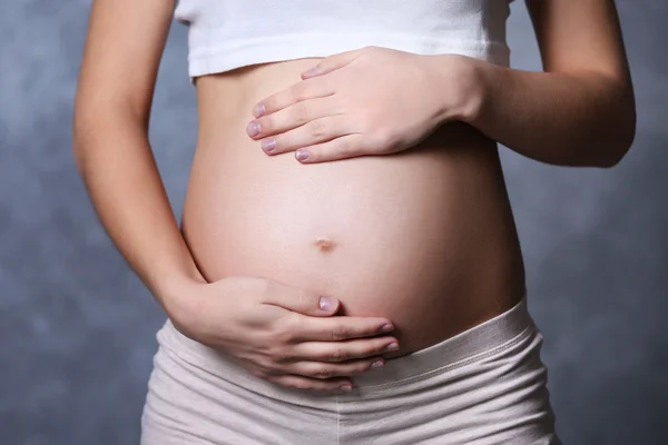 Mujer embarazada sobre fondo de pared gris — Foto de Stock