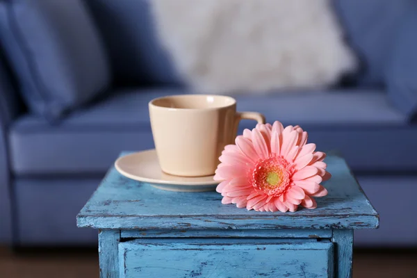 部屋で青いテーブルの上のカップとピンクのガーベラ — ストック写真