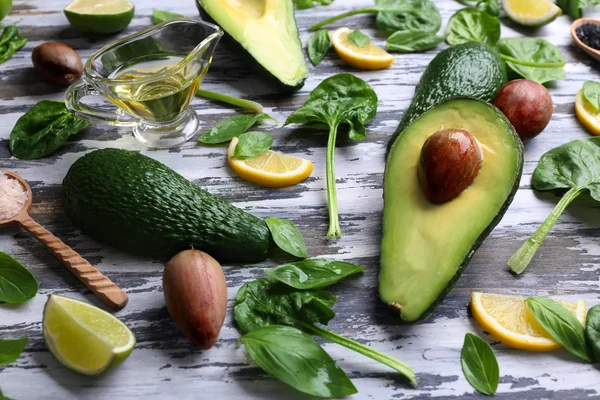 Sliced avocado with spices, fresh spinach, basil and citrus fruit on colored wooden background