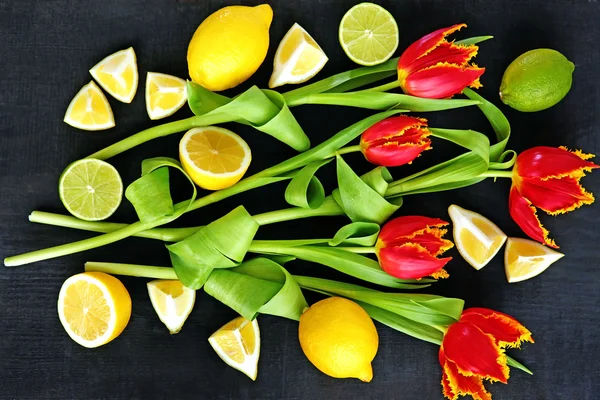 Tulipes et agrumes rouges frais sur fond noir, vue de dessus — Photo