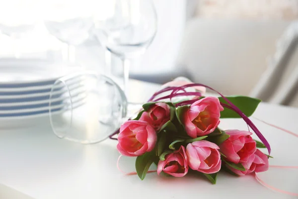 Bouquet of pink tulips and plates on wooden table. — Stock Photo, Image