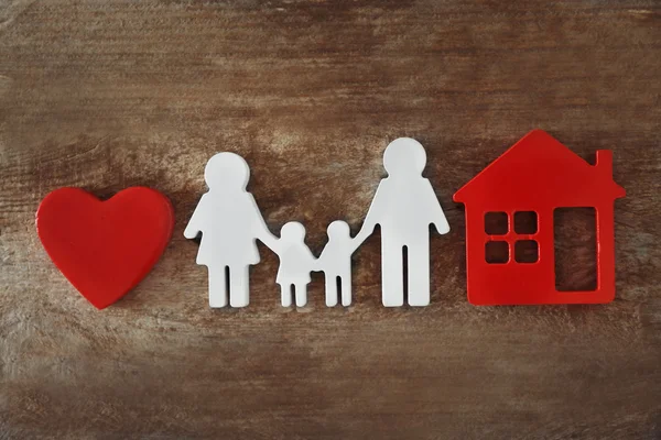 Family figure with a house on wooden  background — Stock Photo, Image