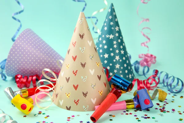 Three Birthday hats with serpentine streamer and noise makers on light blue background — Stock Photo, Image