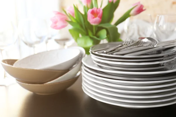 Pilha de chapas, talheres com buquê de tulipas em uma mesa . — Fotografia de Stock