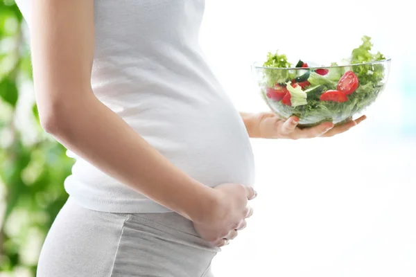 Kobieta w ciąży trzyma szklaną miskę ze świeżą sałatką — Zdjęcie stockowe