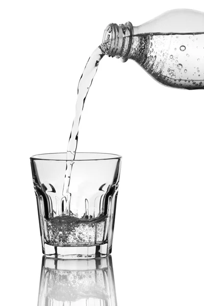 Pouring water from bottle into glass over grey background — Stock Photo, Image