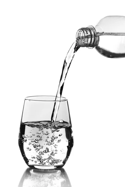 Pouring water from bottle into glass over grey background — Stock Photo, Image