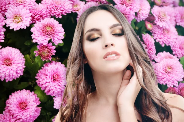 Mooie vrouw op achtergrond met bloemen — Stockfoto