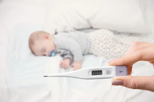 Schlafendes Baby und Hand mit Thermometer — Stockfoto