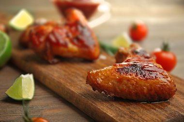Grilled chicken wings with garden-stuff and tomatoes on cutting board clipart