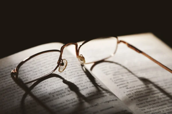 Opened book and eyeglasses on it, close up — Stock Photo, Image