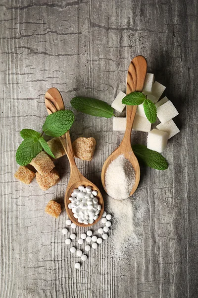 Montón de terrones de azúcar moreno y stevia sobre fondo de madera gris — Foto de Stock