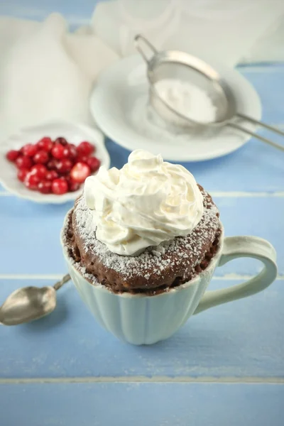 Bolo de caneca com creme e cranberry no fundo de madeira azul — Fotografia de Stock