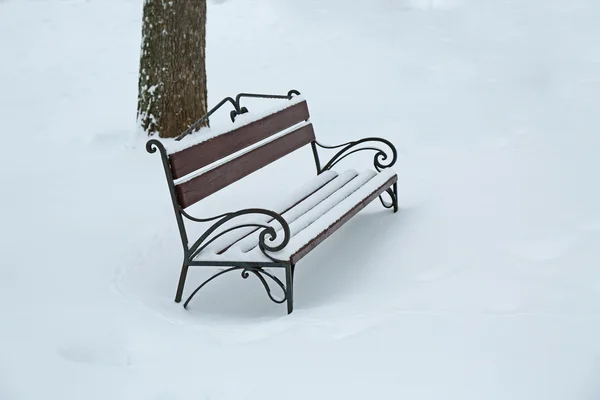 Snow-covered bench in park