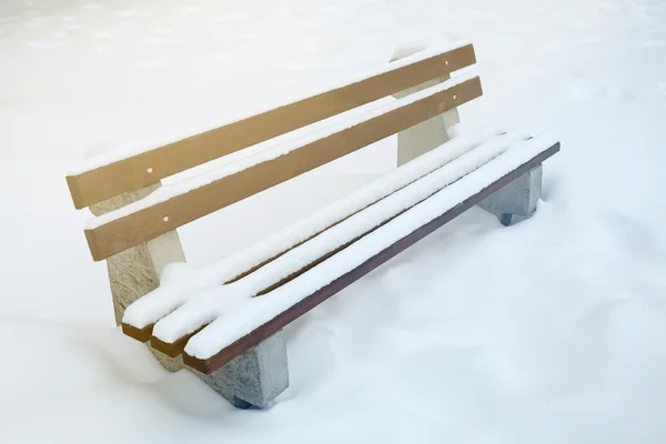 Snow-covered bench in park — Stock Photo, Image