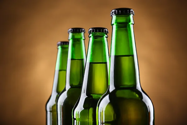 Vier groene glazen flessen bier op donkere verlichte achtergrond, close-up — Stockfoto