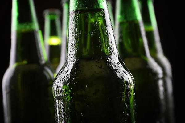 Botellas de vidrio verde de cerveza sobre fondo oscuro, de cerca —  Fotos de Stock