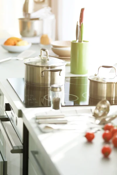 Moderna bord och elspis med köksredskap och grönsaker i köket bredvid fönster — Stockfoto