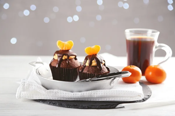 Dos sabrosos cupcakes con rebanada de mandarina y chocolate en una sartén sobre fondo de madera clara — Foto de Stock