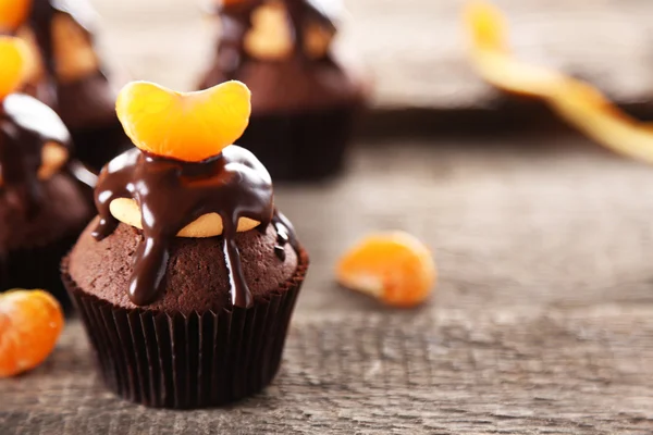 Sabrosos cupcakes con rebanada de mandarina y chocolate sobre fondo de madera —  Fotos de Stock