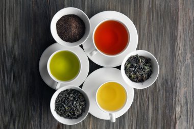 Çay kavramı. Seramik kaseler ve ahşap arka plan üzerinde aromatik çay bardağı kuru çay çeşitleri