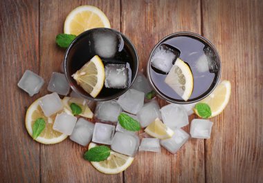 İki bardak kola ile küpleri buz ve limon ahşap masa arka plan üzerinde