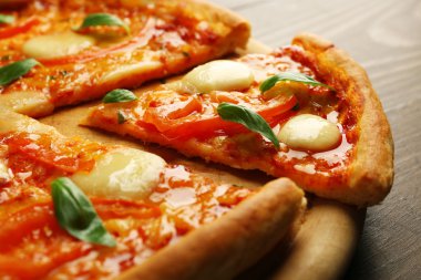 Margherita pizza ahşap arka plan üzerine dilimlenmiş, yakın çekim