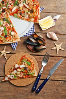 Deniz ürünleri, kırmızı biber ve zeytin pizza ahşap masanın üzerine dilimlenmiş