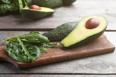 Ispanak ve ahşap kesme tahtası üzerinde roka ile dilimlenmiş avokado