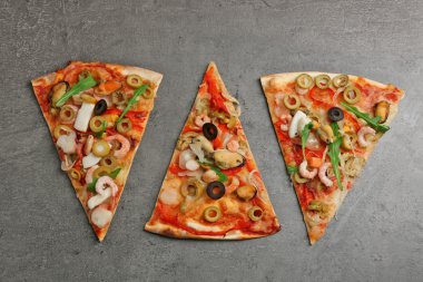 Pizza dilimleri ile deniz ürünleri, kırmızı biber ve zeytin gri arka plan üzerinde