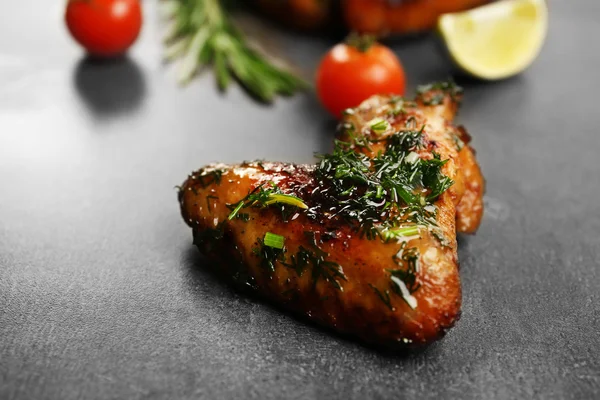 Gebakken kip vleugels met tomaten en rozemarijn op een grijze achtergrond — Stockfoto