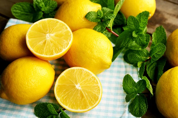 Нарезанные свежие лимоны с зелеными листьями на салфетке крупным планом — стоковое фото
