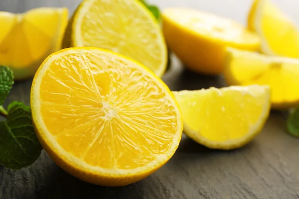 Plakjes verse citroen en limoen op zwarte getextureerde tabel close-up — Stockfoto