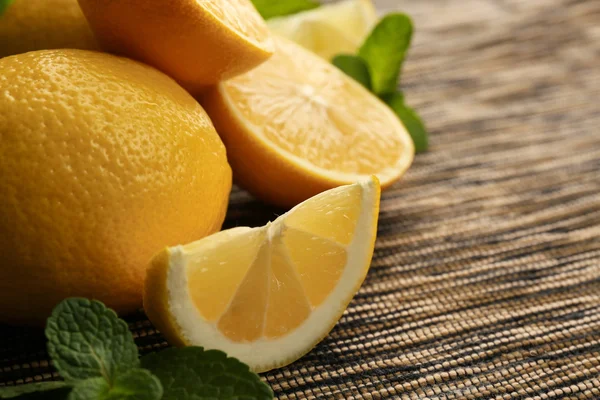 Sliced fresh lemon with green leaves on wooden table closeup — Stock Photo, Image