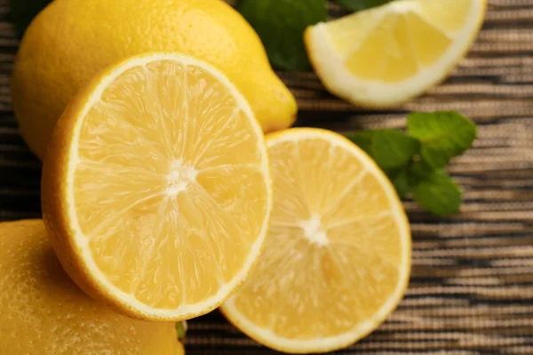 Sliced fresh lemon with green leaves on wooden table closeup — Stock Photo, Image