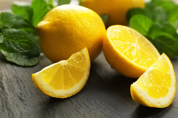 Slices of fresh lemon with green leaves on table closeup — Stock Photo, Image